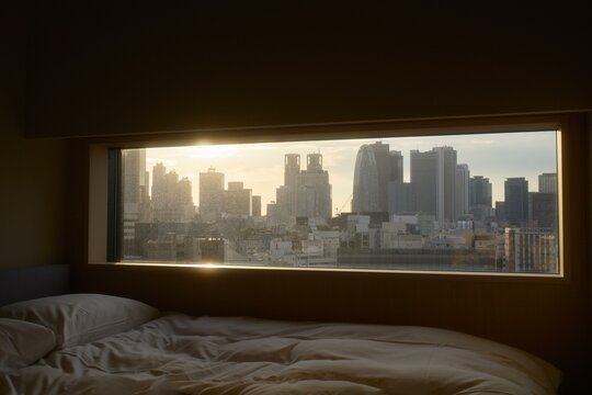 Morning light streaming through cozy bedroom window overlooking Tokyo
