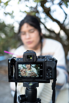 Latin crocheter recording a diy tutorial for her online audience using a mirrorless camera on a tripod