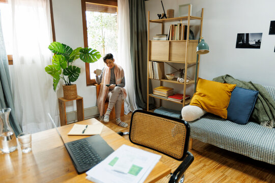 Woman at home office taking a break having tea by the window