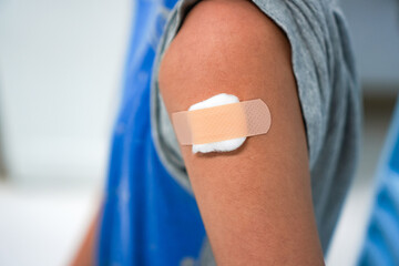 Close-up photograph of a bandage and gauze covering a boy's upper arm after receiving a flu shot at a hospital.