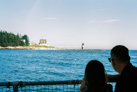 Father and child look at Lighthouse from a boat off Port Clyde, Maine
