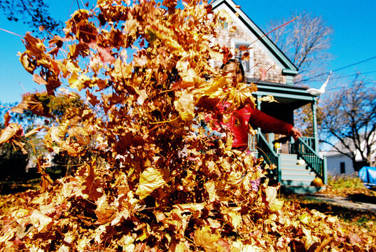 Child throws an armful of leaves while playing outside in autumn