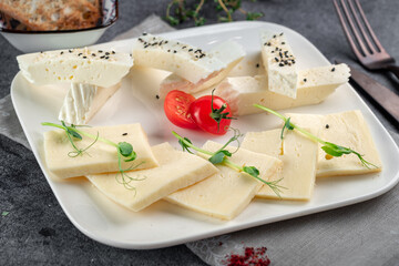 Homemade goat cheese cut into pieces on a white plate. Serbian traditional cheese
