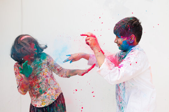 Brother and sister playing holi together with color powder