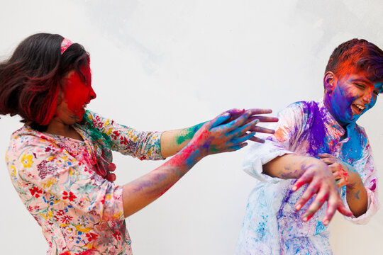 Brother and sister playing holi together with color powder