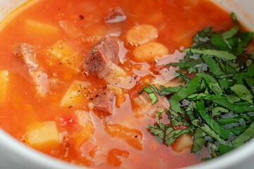 Soup with beans, vegetables and beef - served with parsley, top