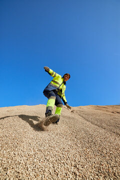 Man in workwear sliding on gravel heap