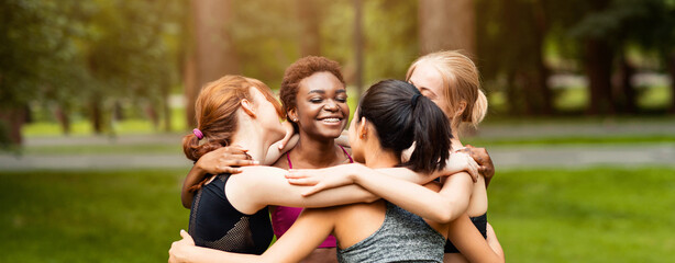 Fototapeta premium Diverse young girls in sportswear hugging after outdoor yoga class at park