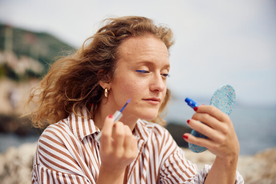 Woman applies makeup on the coast