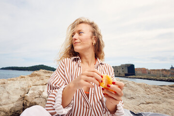 Woman eats an orange on the beach