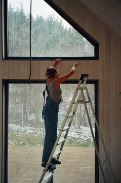 Builder repairing a window in a snowy landscape