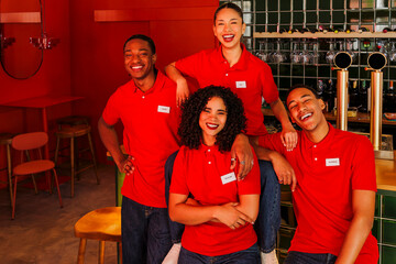 Happy bar staff posing in red uniforms