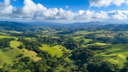 Fototapeta premium An aerial view of green hills blending with vast agricultural fields under a bright blue sky and clouds, illustrating natural beauty, sustainability, and a vibrant rural landscape.