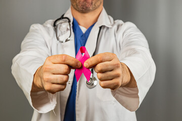 Doctor holding a pink ribbon for breast cancer awareness campaign