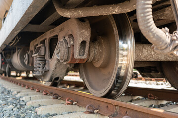 Close-up at freight train wheel part on the rustic railway track. Transportation object.