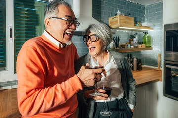 Elderly Multiethnic Couple Enjoying Laughter and Wine in Kitchen