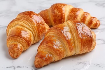 Fototapeta premium Three golden-brown croissants on marble. Perfect for bakery, food blog, or breakfast themes.