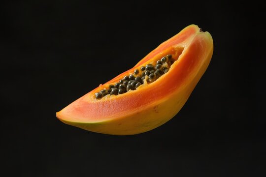 A single ripe papaya slice rests against a dark background