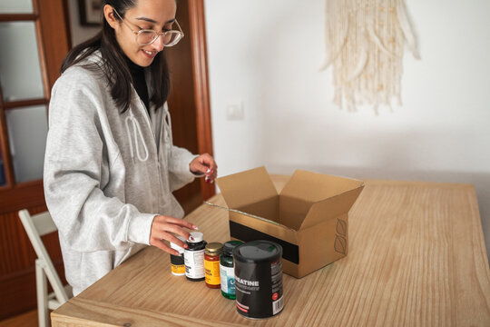 woman at home opening order box for supplements and vitamins