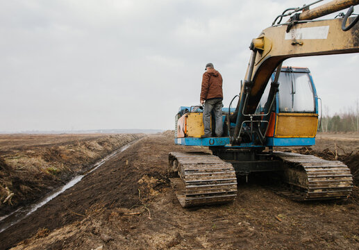 A worker is standing on an excavator.