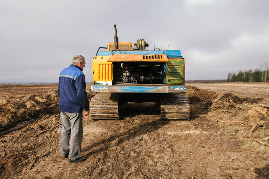 A worker stands at the backhoe.