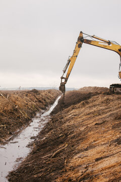 An excavator drips earth near a reclamation canal.