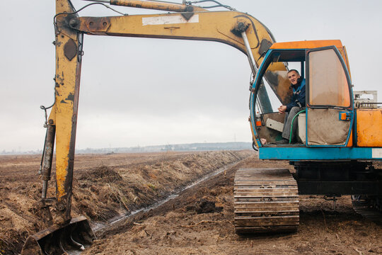 A worker sits in the cab of an excavator.