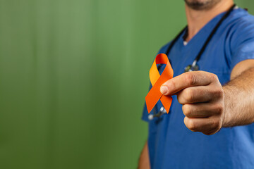 Healthcare professional holding an orange and yellow ribbon to raise awareness