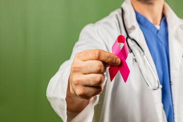Medical professional holding a pink awareness ribbon for breast cancer support