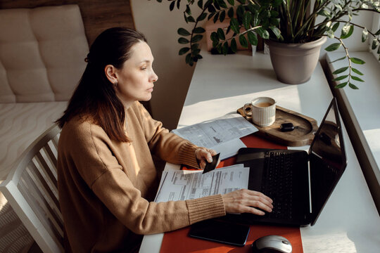 Middle-aged woman paying utility bills from home.