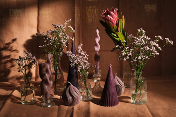 purple candle composition with flowers and natural pink textiles