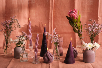 purple candle composition with flowers and natural pink textiles