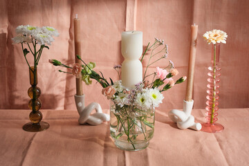 candle composition with flowers and natural pink textiles