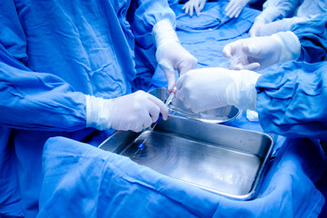 Manos de doctores llenando una jeringa en un quirófano
