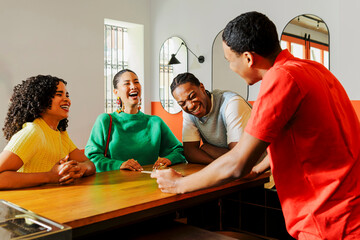 Cheerful friends laughing with waiter at restaurant counter