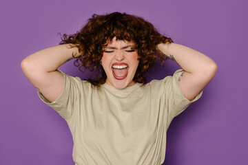 Curvy model expressing joy with curly hair on purple background