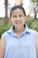 Happy smiling old senior asian woman with positive friendly expression in summer green park in city