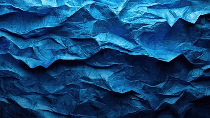 Fototapeta premium A textured, deep blue surface resembling waves or crumpled paper, creating an abstract, visually striking composition.