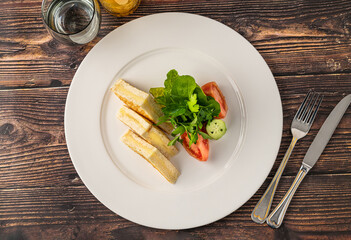 Toast with cheddar cheese and tomatoes and parsley on a white porcelain plate