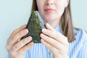Young woman holding korean samgak with tuna close-up on grey background. © TATIANA KIM