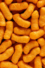 Background of crunchy corn snacks close-up, top view, background of air corn sticks