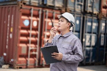 Asia supervisor worker man use walkie talkie working with checking container at container site	