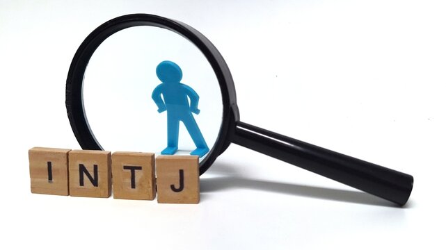 A photo of wooden blocks spelling "INTJ," with a small toy figure placed behind a magnifying glass. INTJ is one of the 16 personality types identified by the Myers-Briggs Type Indicator or MBTI.