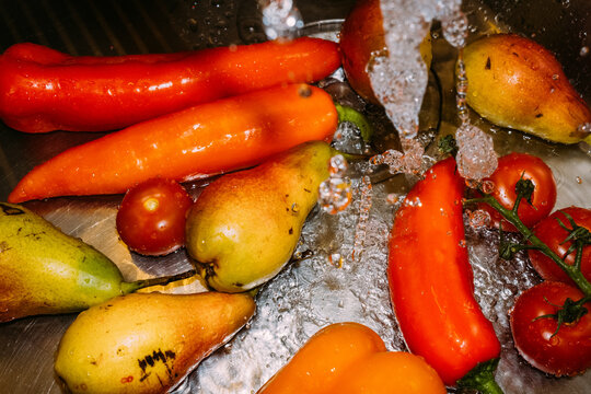 Vegetables and fruits being washed in kitchen sink