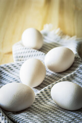 White eggs scattered on a textured linen napkin on a wooden table. Soft natural light enhances the organic and rustic feel, making it a perfect image for Easter, farm-fresh food, and cooking themes