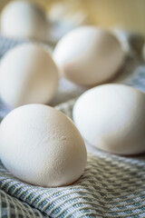 White eggs scattered on a textured linen napkin on a wooden table. Soft natural light enhances the organic and rustic feel, making it a perfect image for Easter, farm-fresh food, and cooking themes