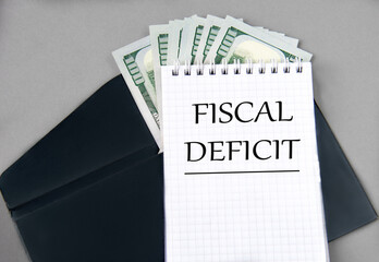 FISCAL DEFICIT - words in a notebook against the background of a black envelope and banknotes