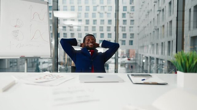 Happy boss in his office, African American man relaxing on chair and smiling. Office worker enjoying new office room and successful career in corporation, good mood and positivity, black male person