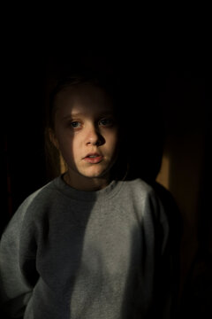 A girl stands in a sliver of light