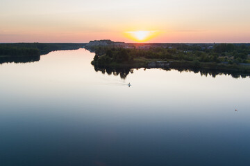 Summer sunset in Rummu: two people on paddleboards enjoy the fiery sky over the calm water of this amazing quarry.